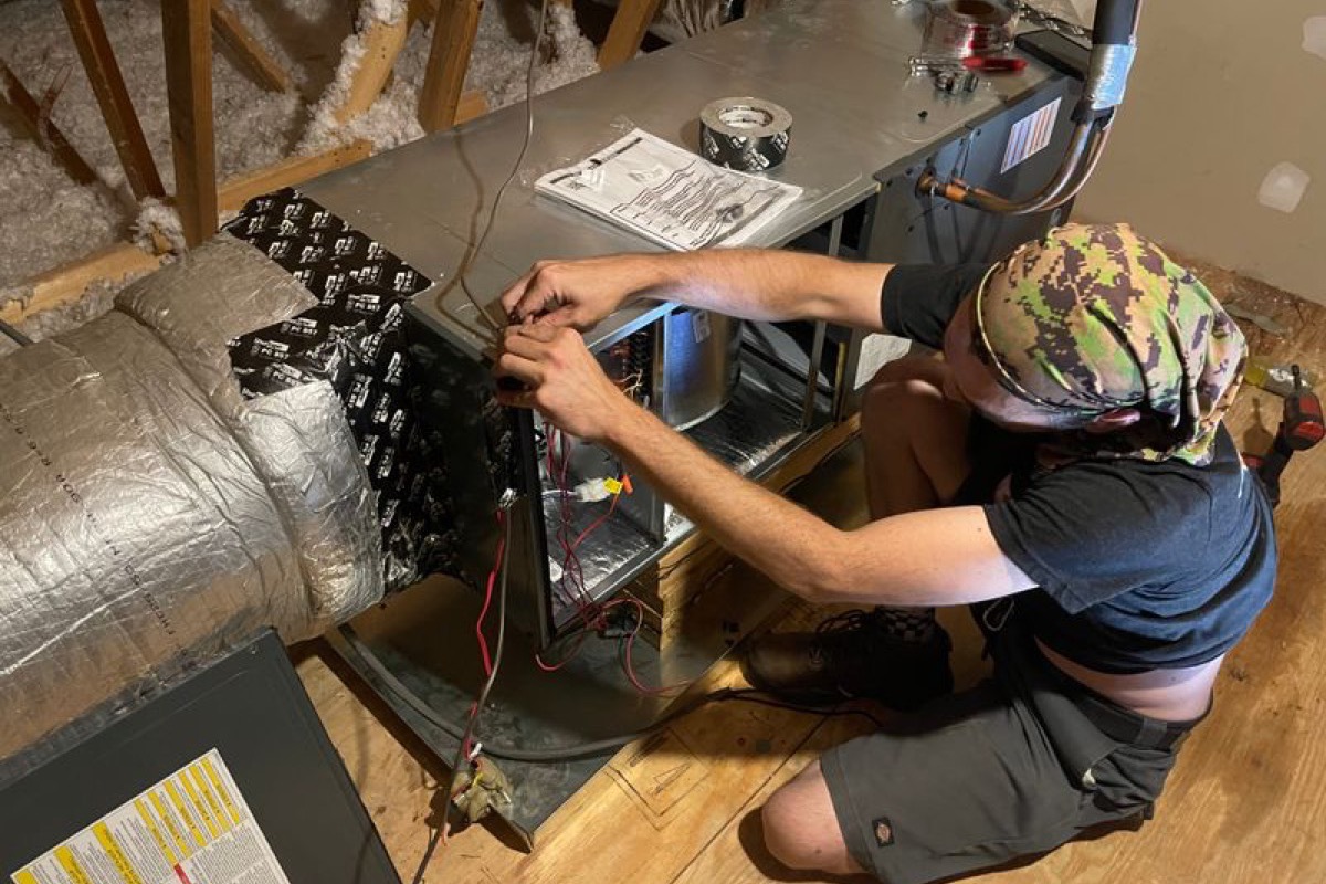 Technician checking wiring inside an indoor HVAC air handler
